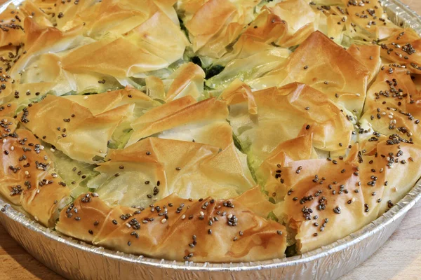 Concept of greek cuisine. Homemade Spanakopita pie. Greek spinach feta cheese pie on wooden table.