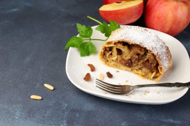 Ev yapımı elmalı turta, fillo pastası, tarçın, sultanalar, gri arka planda badem. Apfelstrudel. Gıda tarifi geçmişi, Avusturya Almanya yemekleri.