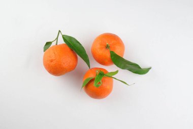 Beyaz arka planda yaprakları olan taze mandalina meyveleri. Tam üstte.