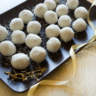 Beyaz arka planda cam bir kapta hindistan cevizi ve beyaz çikolatadan yapılmış ev yapımı yuvarlak şekerler. Raffaello şekeri. Noel süsü. Uzayı kopyala Tam üstte.