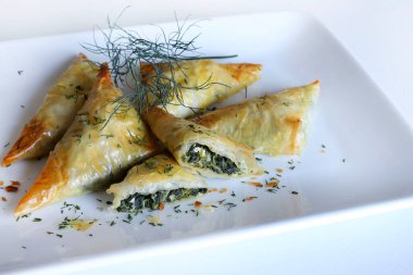 Geleneksel Yunan mutfağı. Spanakopita, ıspanaklı gevrek fillo hamur işi üçgeni, beyaz arka planda beyaz peynir. Tam üstte. Boşluğu kopyala.