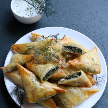 Geleneksel Yunan mutfağı. Spanakopita, gri arka planda ıspanak, feta, dereotu ve tzatziki soslu çıtır fileto. Tam üstte. Boşluğu kopyala.