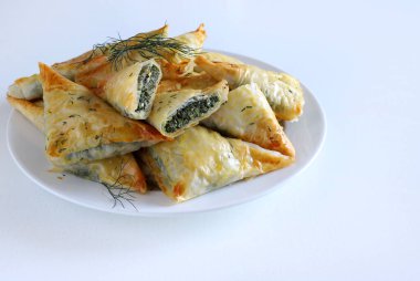 Geleneksel Yunan mutfağı. Spanakopita, ıspanaklı gevrek fillo hamur işi üçgeni, beyaz arka planda beyaz peynir. Tam üstte. Boşluğu kopyala.
