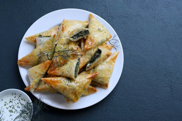 Geleneksel Yunan mutfağı. Spanakopita, gri arka planda ıspanak, feta, dereotu ve tzatziki soslu çıtır fileto. Tam üstte. Boşluğu kopyala.