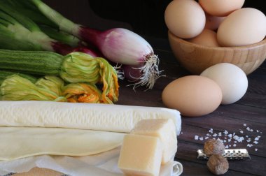 Puf böreği, kabak turtası, Tropea kırmızı soğanı, yumurta, peynir ve siyah zemin üzerine baharat. Ev yapımı konsept. Yakın plan..