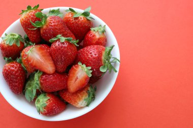 Kırmızı arka planda izole edilmiş bir kasede taze organik çilekler. Bahar meyvesi Tam üstte. Boşluğu kopyala.