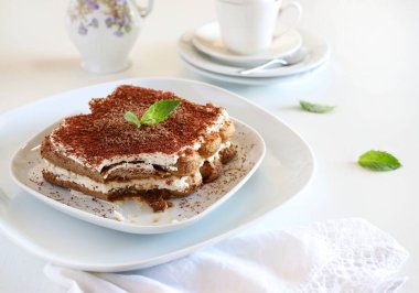 Tiramisu kahvesi. Beyaz arka planda beyaz bir tabakta leydiparmak ve mascarpone kremalı klasik kahve tiramisusu. İtalyan tatlısı.