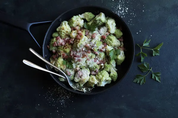 Kavrulmuş brokoli soslu Romanesco jambon ve parmesanlı koyu arka planda. İtalyan yemeği. Tam üstte.