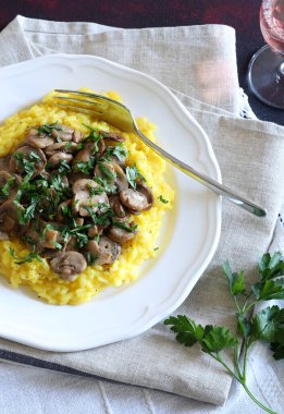Mantarlı leziz safran risotto ve beyaz tabakta maydanoz. Geleneksel İtalyan pilavı. Tam üstte.