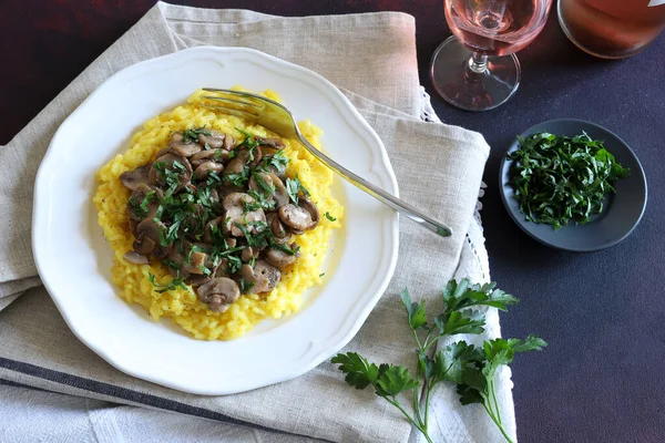 Mantarlı leziz safran risotto ve beyaz tabakta maydanoz. Geleneksel İtalyan pilavı. Tam üstte.