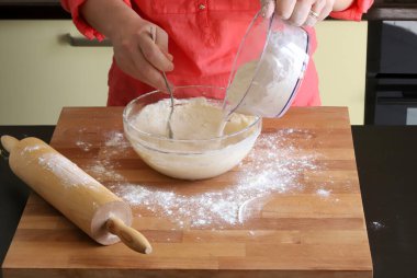 Geleneksel ev yapımı hamur hazırlıyorum. Un kaplı bir masada ekmek, pizza ya da kurabiye yapmak için taze hamur yoğuran kadın ellerine yakından bakın. Evde yemek pişirmek..