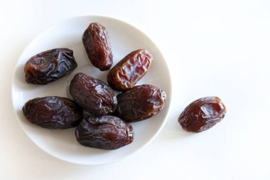 Beyaz arka planda izole edilmiş beyaz bir tabakta kuru hurma grubu. Genel bakış. Boşluğu kopyala.