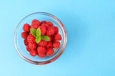 Mavi arka planda nane yapraklı taze ahududu. Sağlıklı yiyecekler. Tam üstte. Tuvaller ve arka plan için mükemmel..