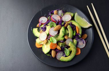 Taze avokado ve koyu arkaplanda badem salatası. Sağlıklı yiyecekler. Tam üstte. Boşluğu kopyala.