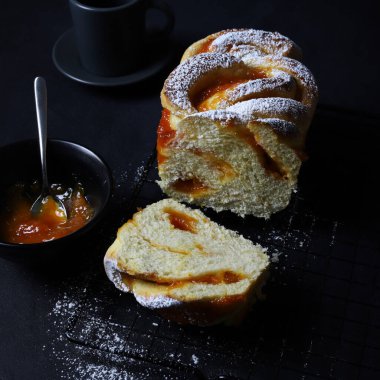 Babka ya da koyu arkaplanda kayısı reçeli Brioche ekmeği. Örülmüş ya da rulo ekmek. Kahvaltı için ev yapımı hamur işi..