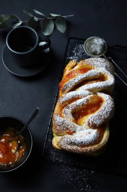 Babka ya da koyu arkaplanda kayısı reçeli Brioche ekmeği. Örülmüş ya da rulo ekmek. Kahvaltı için ev yapımı hamur işi..