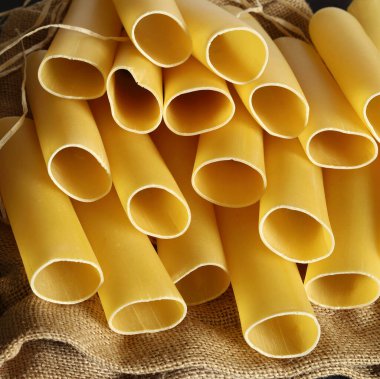 Köy arka planında çiğ makarna yalıtılmış. Cannelloni makarna tüpleri. İtalyan yemeği konsepti. Uzayı kopyala Yakın plan..