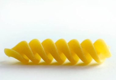 Geleneksel İtalyan makarnası. Bir parça pişmemiş fusilli makarna beyaz arka planda izole edilmiş. Un ürünleri. Sağlıklı organik gıda. Yakın plan..