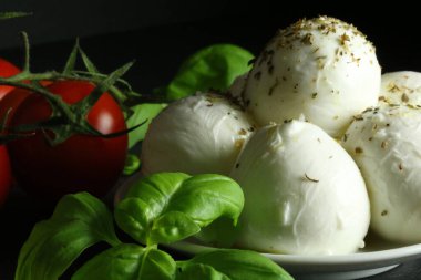 Campagna 'dan İtalyan bufalo mozzarella peyniri, koyu arkaplanda fesleğen yaprağı ve domates. Taze İtalyan peyniri. Boşluğu kopyala.