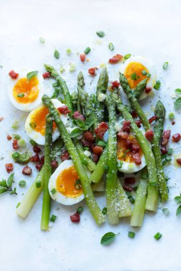 Kuşkonmaz, haşlanmış yumurta, pastırma, beyaz arka planda izole edilmiş otlar. Lezzetli bahar yemeği. Sağlıklı gıda konsepti. Genel Görünüm.