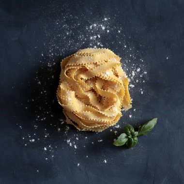 İtalyan makarnası. Koyu arkaplanda izole edilmiş kıvırcık pappardelle makarna. Sağlıklı yiyecekler. Genel bakış. Yemek pişirme konsepti. Boşluğu kopyala.