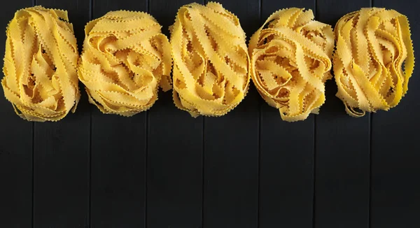意大利面食 卷曲的意大利面在黑色背景上被分离出来 健康食品 俯瞰头顶 烹饪的概念 复制空间 — 图库照片