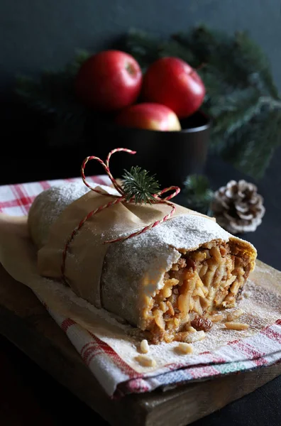 Homemade apple strudel stuffed with apples, cinnamon, pine nuts on rustic background. Christmas apple strudel. Austrian Germany food. Directly above.