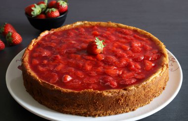 Masada çilek soslu ev yapımı cheesecake. Arka planda taze çilekler. Yakın plan. Boşluğu kopyala.