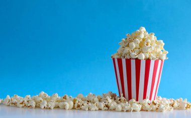 Mavi arka planda izole edilmiş lezzetli tuzlu patlamış mısır. Sinema, sinema ve eğlence konsepti. Boşluğu kopyala.