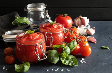 Klasik ev yapımı İtalyan domates sosu makarna için fesleğen ya da siyah arka planda cam kavanozlarda pizza. İtalyan yemeği konsepti. Yakın plan. Boşluğu kopyala.