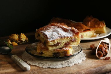 Geleneksel Yunan mutfağı. Lezzetli Bougatsa, krema ve sultanla doldurulmuş pudra şekerle süslenmiş fillo hamur işi. Yakın plan..