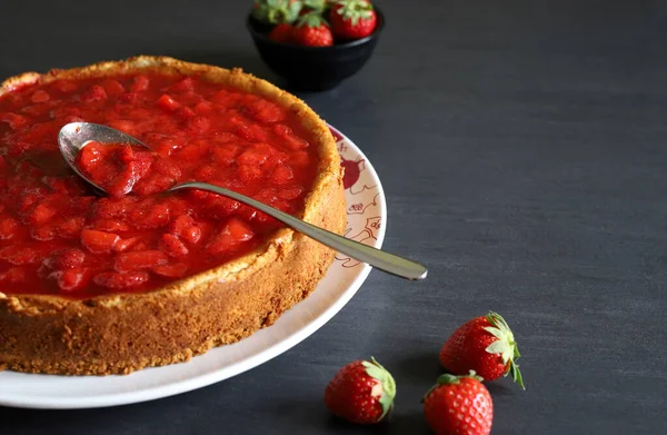 Masada çilek soslu ev yapımı cheesecake. Arka planda taze çilekler. Yakın plan. Boşluğu kopyala.