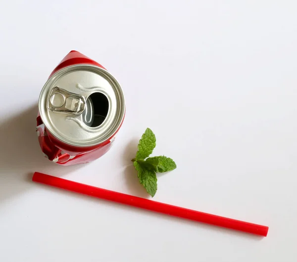 Crumpled aluminum can, red drinking straw and mint leaves isolated on white background. Overhead view. Copy space.
