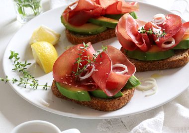 Beyaz arka planda Bresaola (tütsülenmiş et) ile avokado tostu. Sağlıklı gıda konsepti. Genel bakış. Boşluğu kopyala.