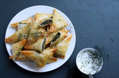 Geleneksel Yunan mutfağı. Spanakopita, gri arka planda ıspanaklı ve fetalı gevrek fileto üçgenleri. Tam üstte. Boşluğu kopyala.