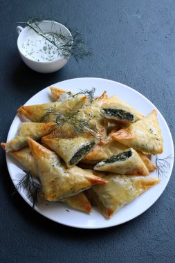 Geleneksel Yunan mutfağı. Spanakopita, gri arka planda ıspanaklı ve fetalı gevrek fileto üçgenleri. Tam üstte. Boşluğu kopyala.