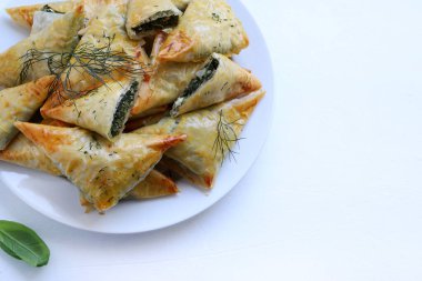 Geleneksel Yunan mutfağı. Spanakopita, beyaz arka planda ıspanak, feta ve taze dereotlu gevrek fileto üçgenleri. Uzayı kopyala Genel Görünüm.