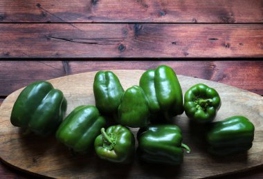 Kırsal ahşap arka planda izole edilmiş bir grup taze yeşil biber. Vejetaryen yemeği. Genel bakış. Boşluğu kopyala.