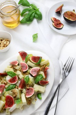 Beyaz arka planda hindiba, fındık, peynir ve bal ile taze incir salatası. Sağlıklı yiyecekler. Yukarıdan görüntüle.