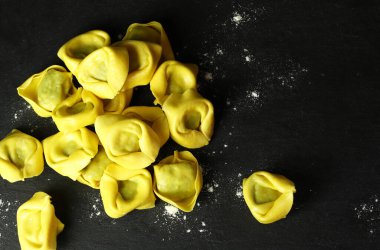 İtalyan yemeği. Ev yapımı tortellini siyah arka planda izole edilmiş. Doldurulmuş makarna. Genel bakış. Boşluğu kopyala.