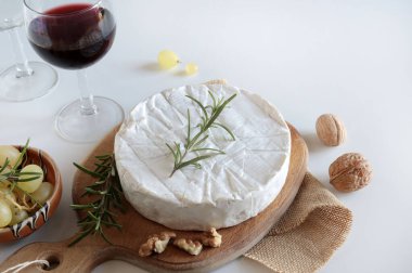 Fındıklı peynir, üzüm ve şarap beyaz arka planda ahşap kesme tahtasının üzerinde. Camembert peyniri. Genel Görünüm.