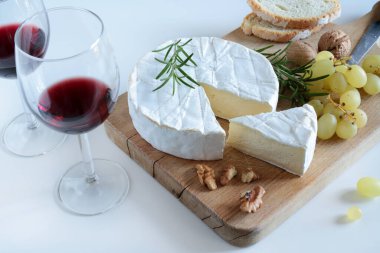 Fındıklı peynir, üzüm ve şarap beyaz arka planda ahşap kesme tahtasının üzerinde. Camembert peyniri. Genel Görünüm.