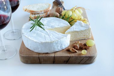 Fındıklı peynir, üzüm ve şarap beyaz arka planda ahşap kesme tahtasının üzerinde. Camembert peyniri. 