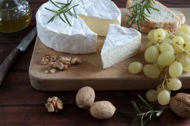 Fransız peyniri. Fındıklı peynir, üzüm ve şarap kırsal arka planda ahşap kesme tahtasının üzerinde. Camembert peyniri. 