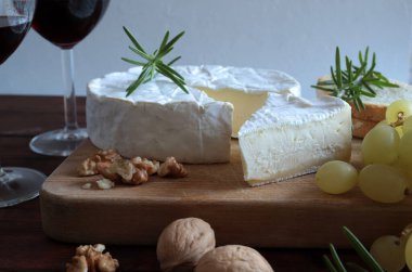 Fransız peyniri. Fındıklı peynir, üzüm ve şarap kırsal arka planda ahşap kesme tahtasının üzerinde. Camembert peyniri. 
