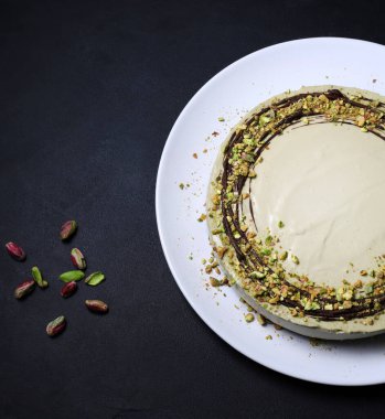 Lezzetli fıstıklı cheesecake servis edilmeye hazır, gri arka planda doğranmış şam fıstıklı kremalı kek. Genel Görünüm.