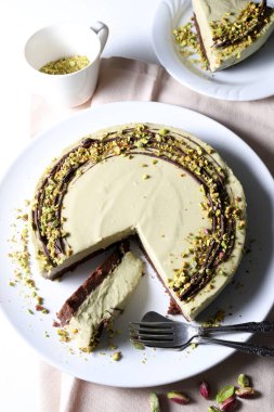 Lezzetli fıstıklı cheesecake servis edilmeye hazır, beyaz arka planda doğranmış şam fıstıklı kremalı kek. Genel Görünüm.