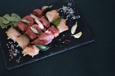 Siyah arka planda çiğ et ve pastırmalı şişler. Uzayı kopyala Genel Görünüm.