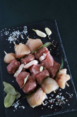 Siyah arka planda çiğ et ve pastırmalı şişler. Uzayı kopyala Genel Görünüm.