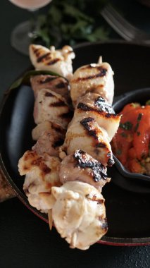 Hindi, sosis, domuz eti, sebze, otlar ve siyah arka planda bir bardak şarap. Genel Görünüm.